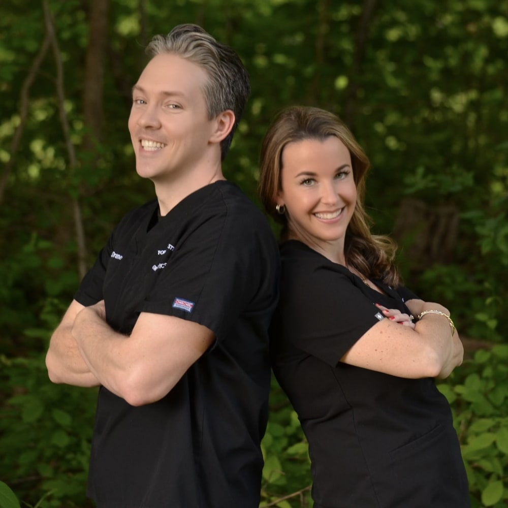 Dr. Drane and Dr. Christie are posing with their backs up against one another and their arms crossed.