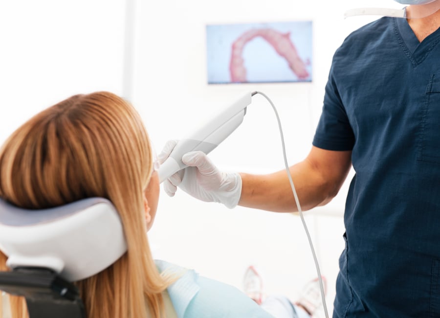 A patient sits while the orthodontist uses the intraoral scanner device.